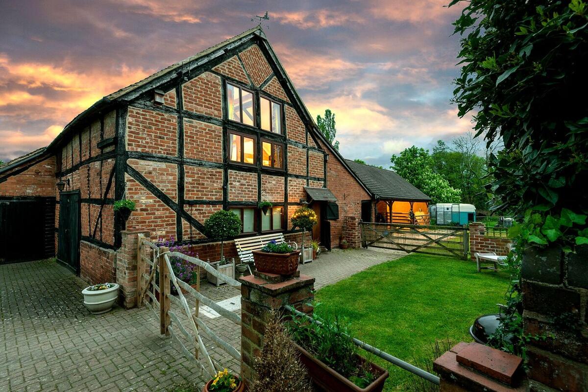 Hop Pickers Barn, a black-and-white timbered barn, lit up at sunset