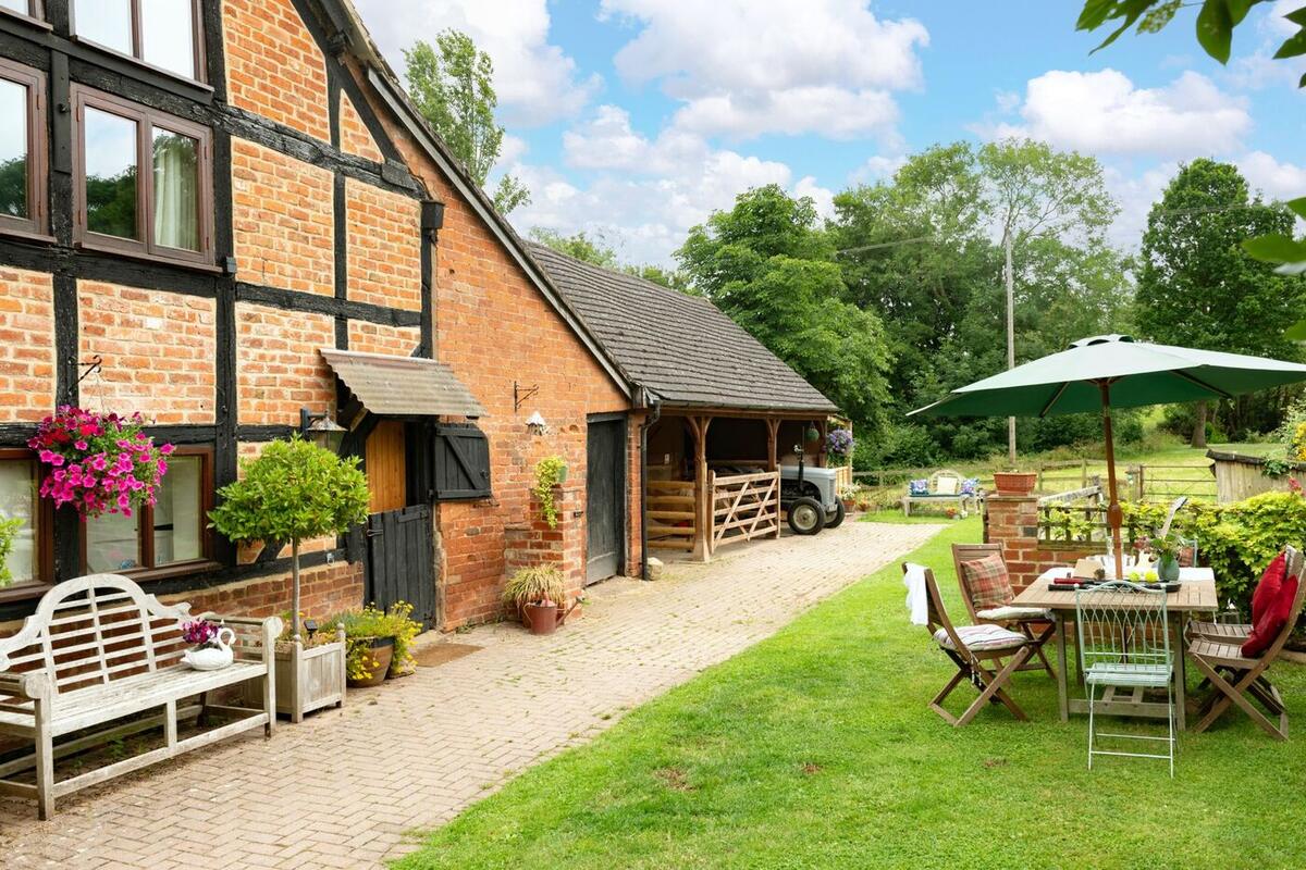 Timbered barn front with garden, table and parasol