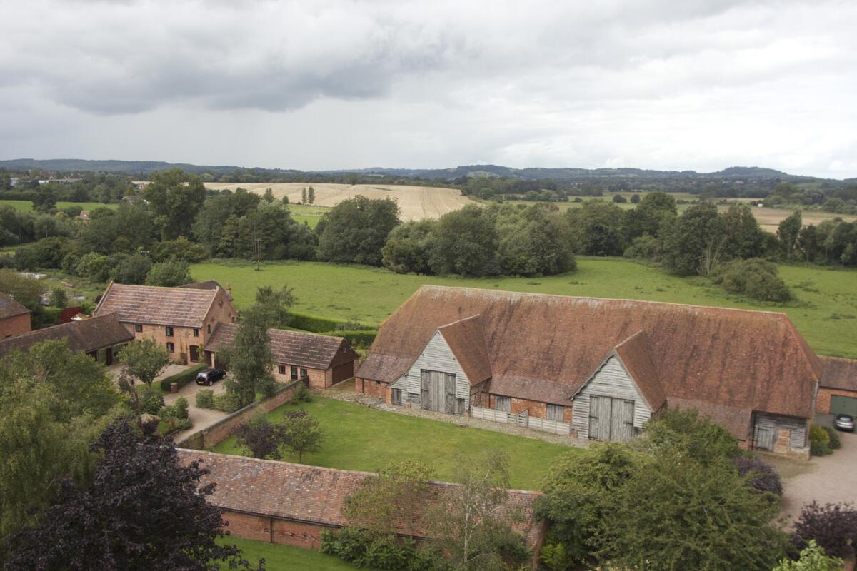Farmland, hedges and red-roofed farm buildings seen from above