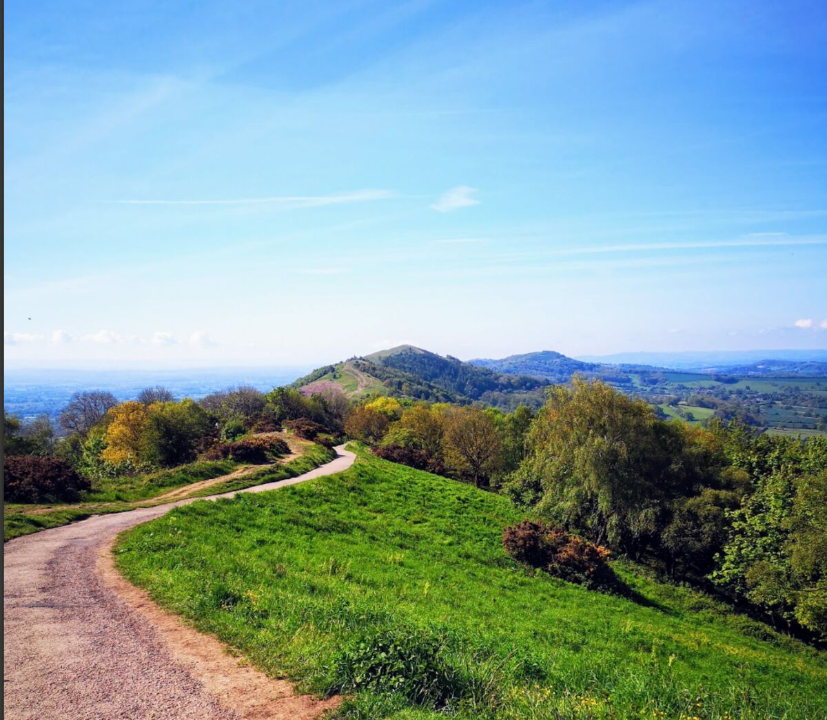 Path along a green hill ridge under a blue sky