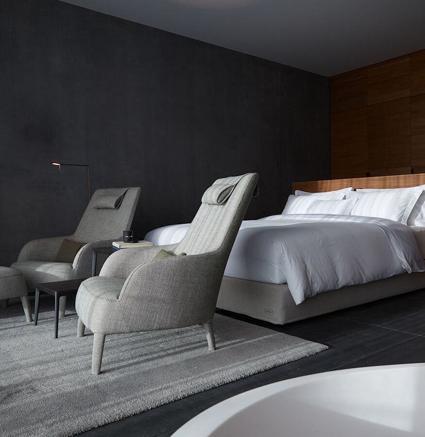 Armchairs, bed and a freestanding bath in the suite